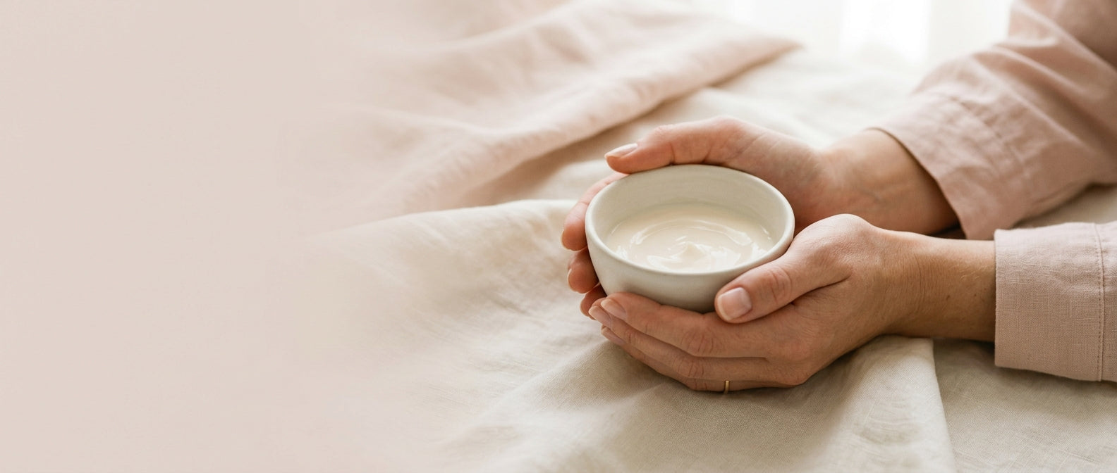 Hands cradling porcelain bowl of pale cream — sensitivity and redness